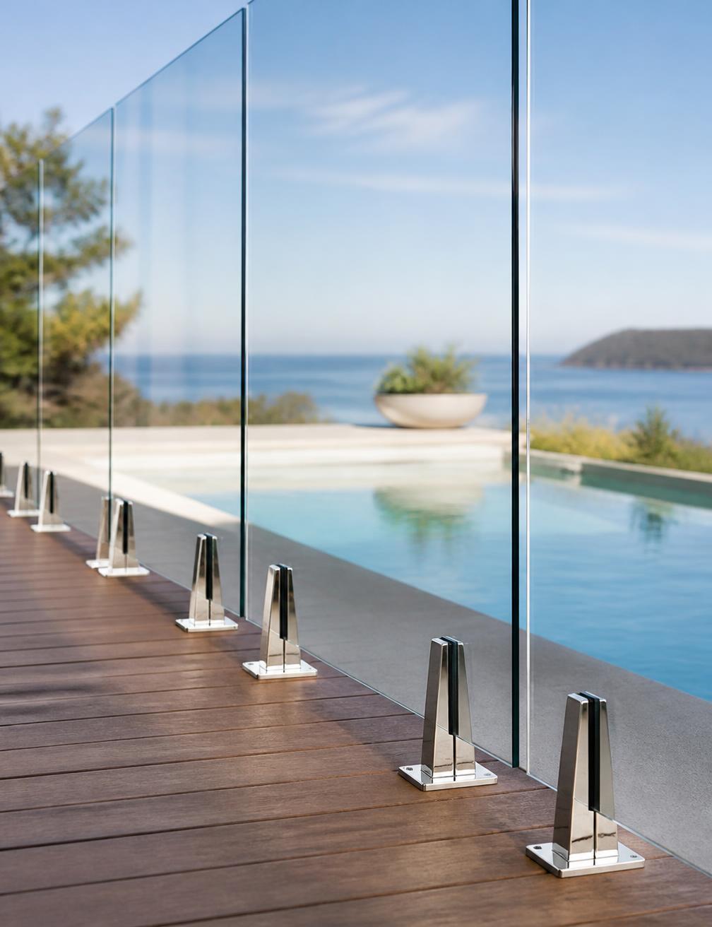 Close-up of frameless glass pool fencing with stainless steel spigots on timber decking